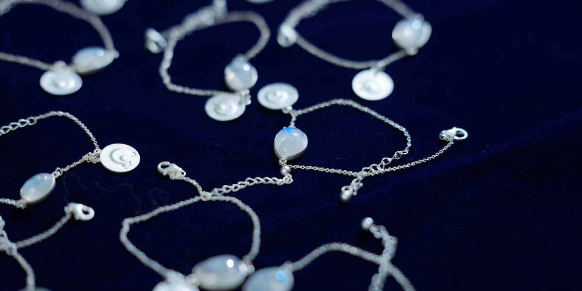 Rainbow moonstone bracelets laid out together on navy velvet, the nearest in focus