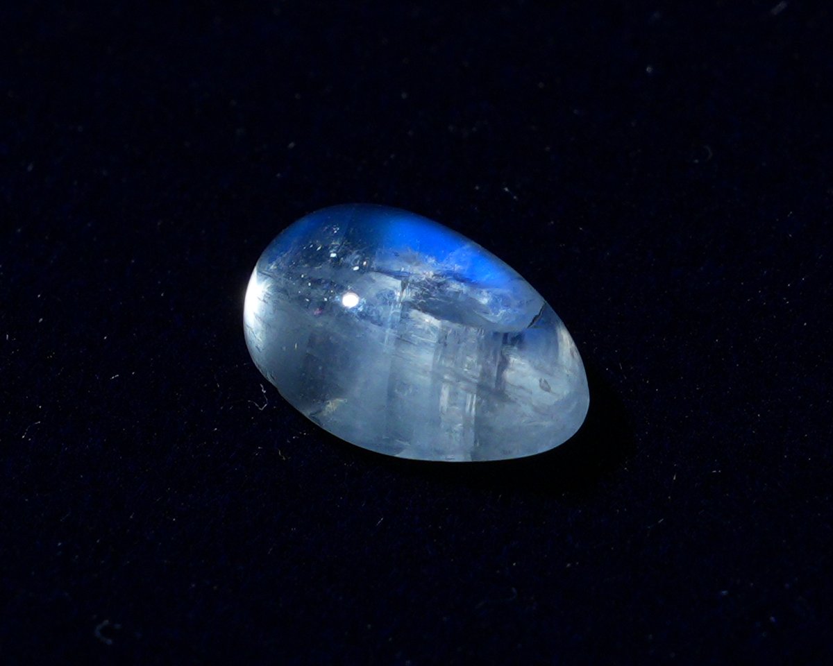 A single natural moonstone on navy velvet