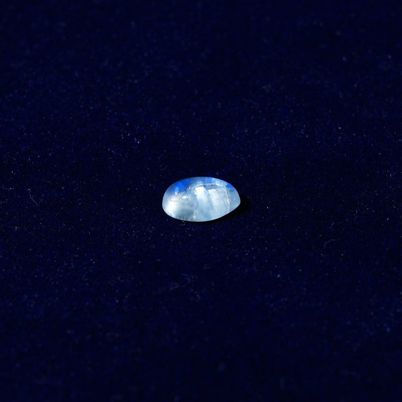 A single natural rainbow moonstone on navy velvet